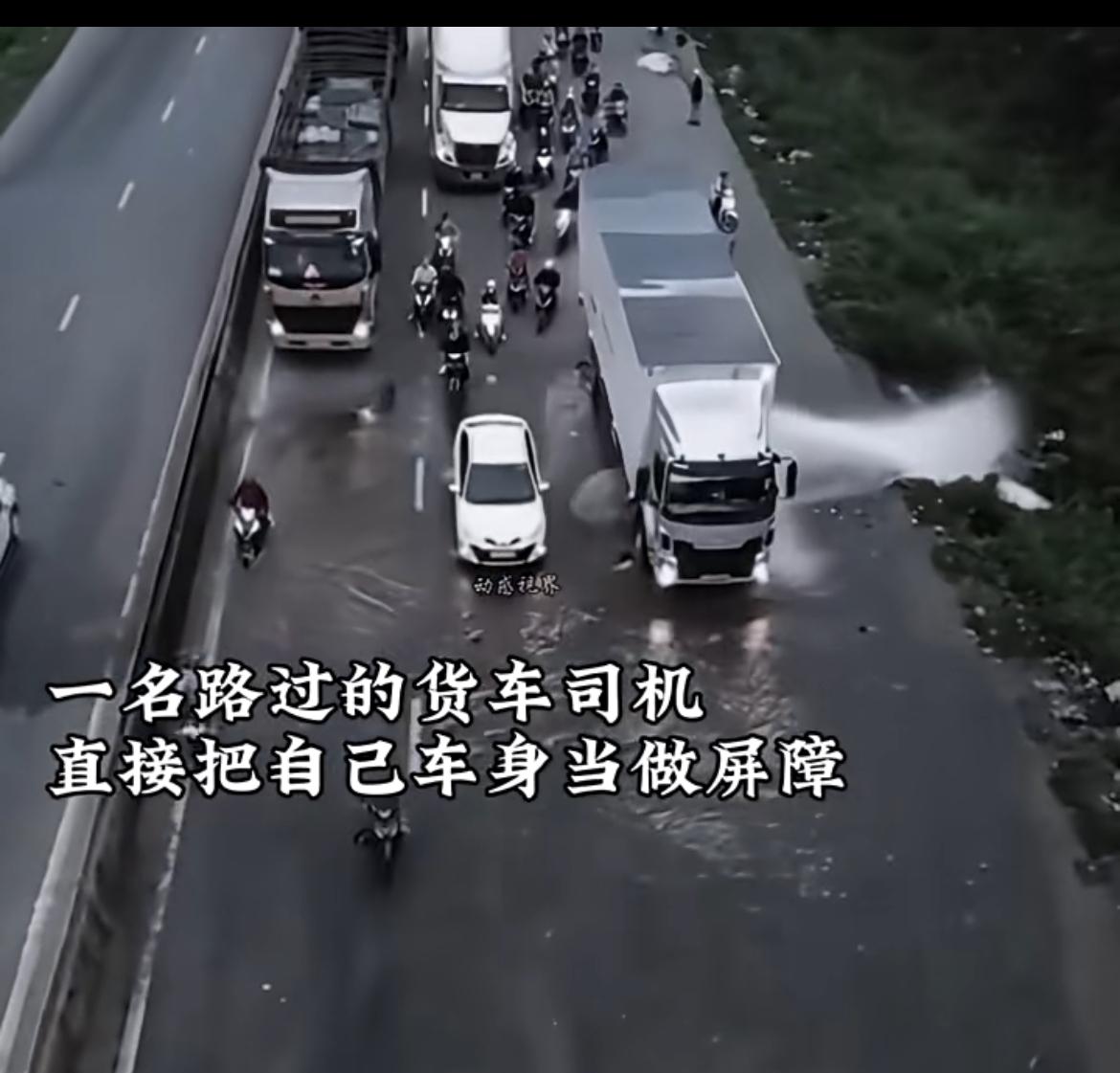 一条马路边上的水管爆裂喷水，导致路上行人过往困难，这时候，一名路过的货车司机，将