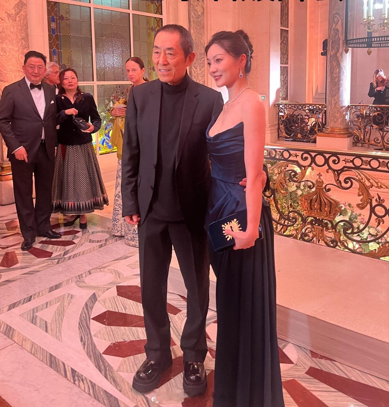 张艺谋一家参加巴黎名媛舞会  张艺谋蹲着给妻子拍照 张艺谋一家四口参加巴黎名媛舞