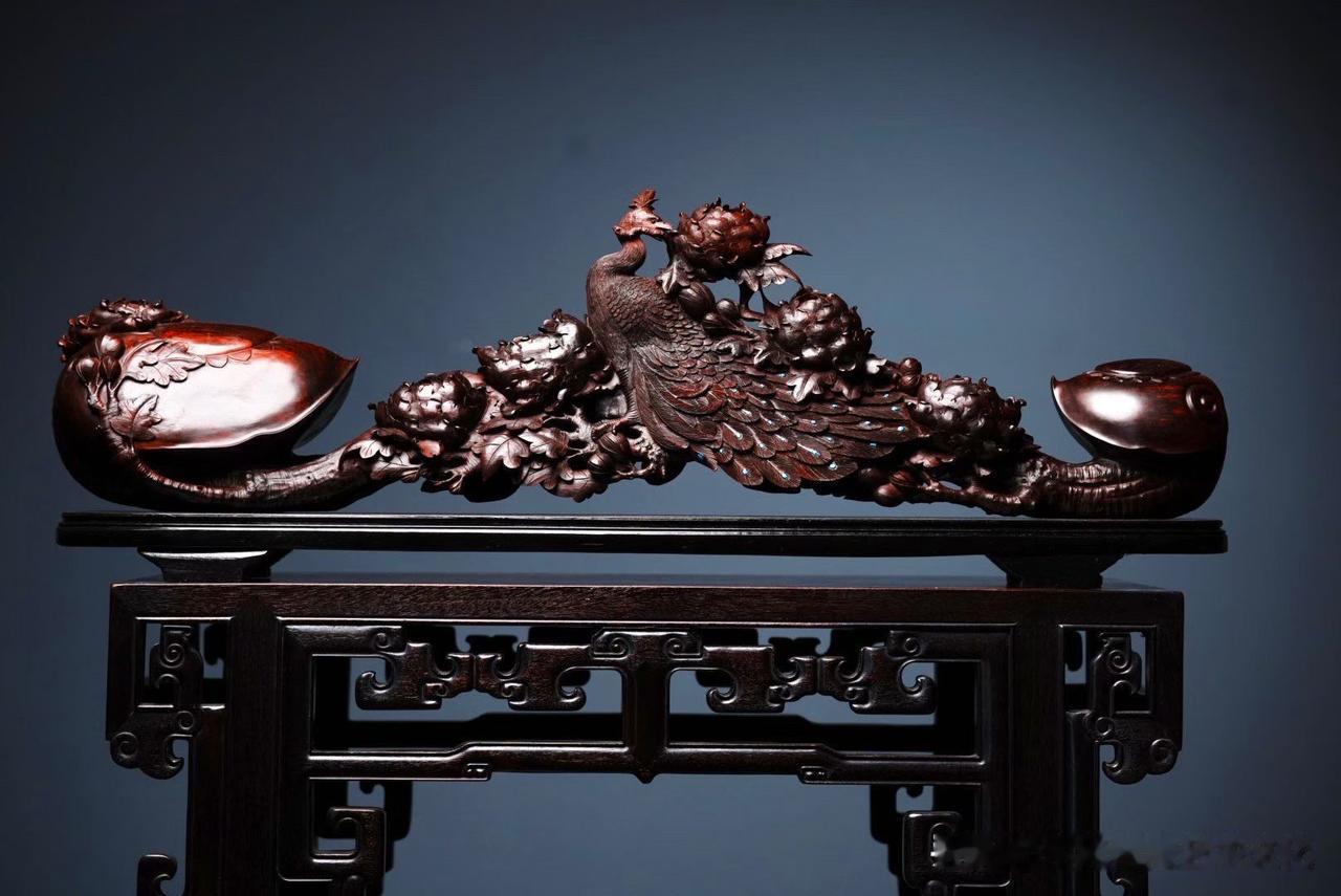 孔雀回首，牡丹盛放，一柄如意把两种华美的意象融在了一起。

小叶紫檀整料雕琢，深