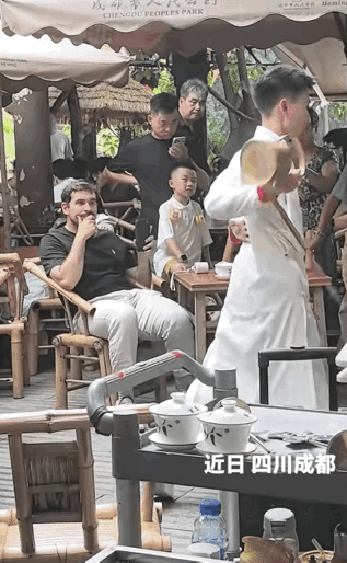 四川成都， 一家老茶馆里，一个白人老外坐在竹椅上，面前不是茶杯，而是一把长嘴铜壶