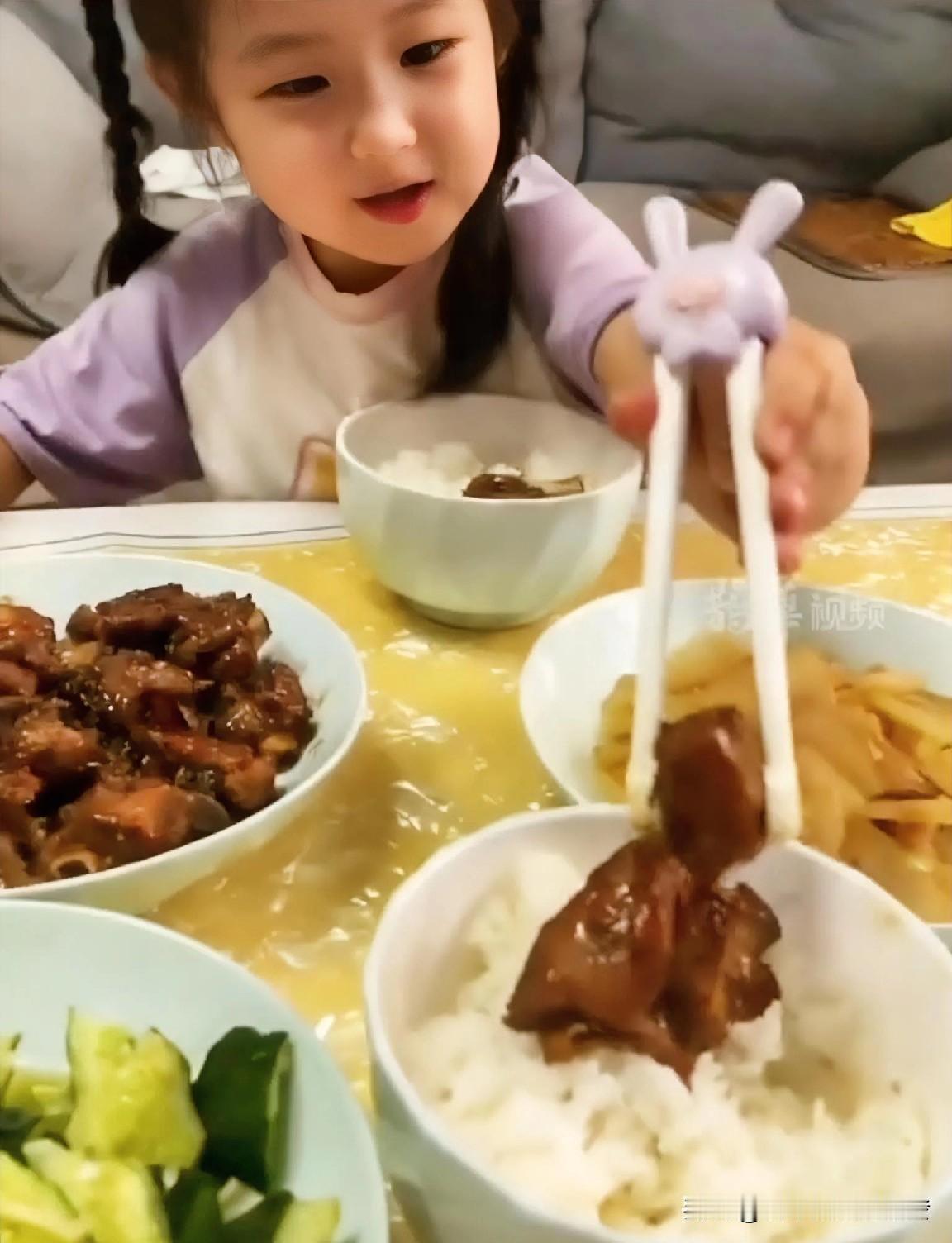 女儿用筷子夹起米饭碗里的一块肉，抬头问妈妈：“爸爸呢？”妈妈回答：“爸爸在加班呢