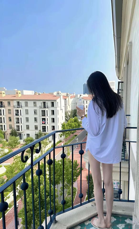 阳台上，女孩喝着水，看着风景。