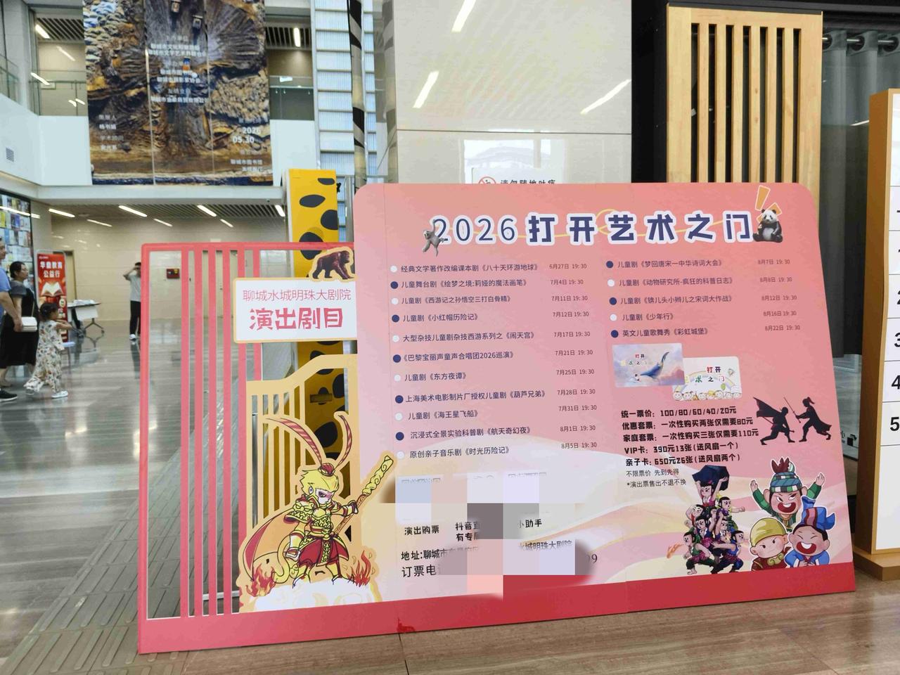 聊城市图书馆里摆上“2026打开艺术之门”演出广告牌，我感觉让文化氛围更浓了。