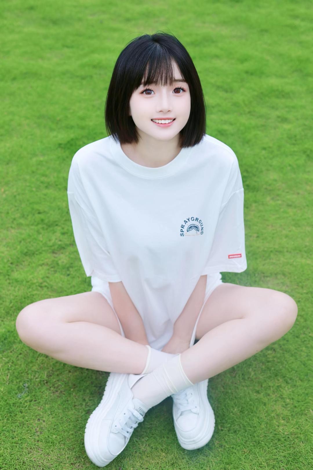 青春洋溢的少女，白色T恤搭配运动鞋，坐在绿草地上，微笑着迎接美好一天！🌞💚