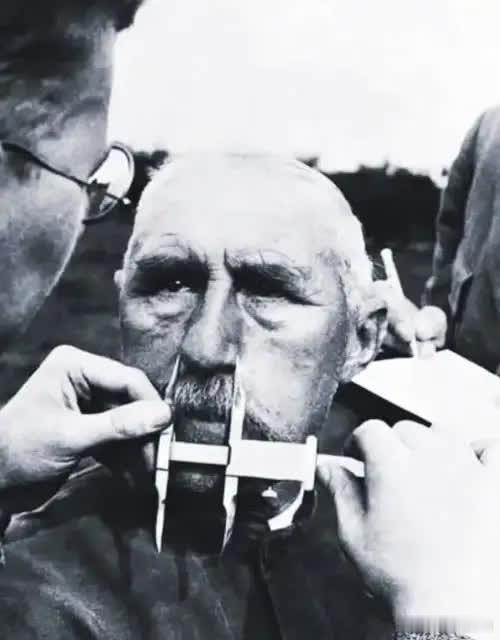 德国党卫军正在拿标尺，测量一个老人的鼻子。这是当时占领区普遍的现象，因为他们相信