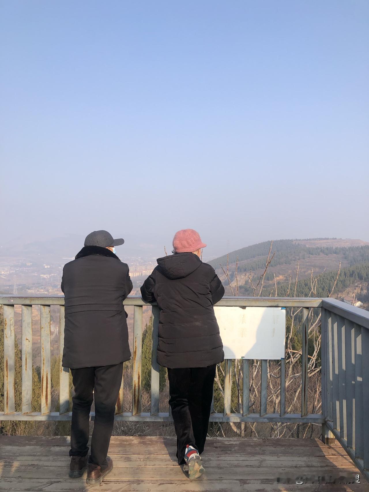 昨天爬山时拍到的一幕，两位老人肩并肩倚着栏杆，安安静静望着远处的山景，背影看着特