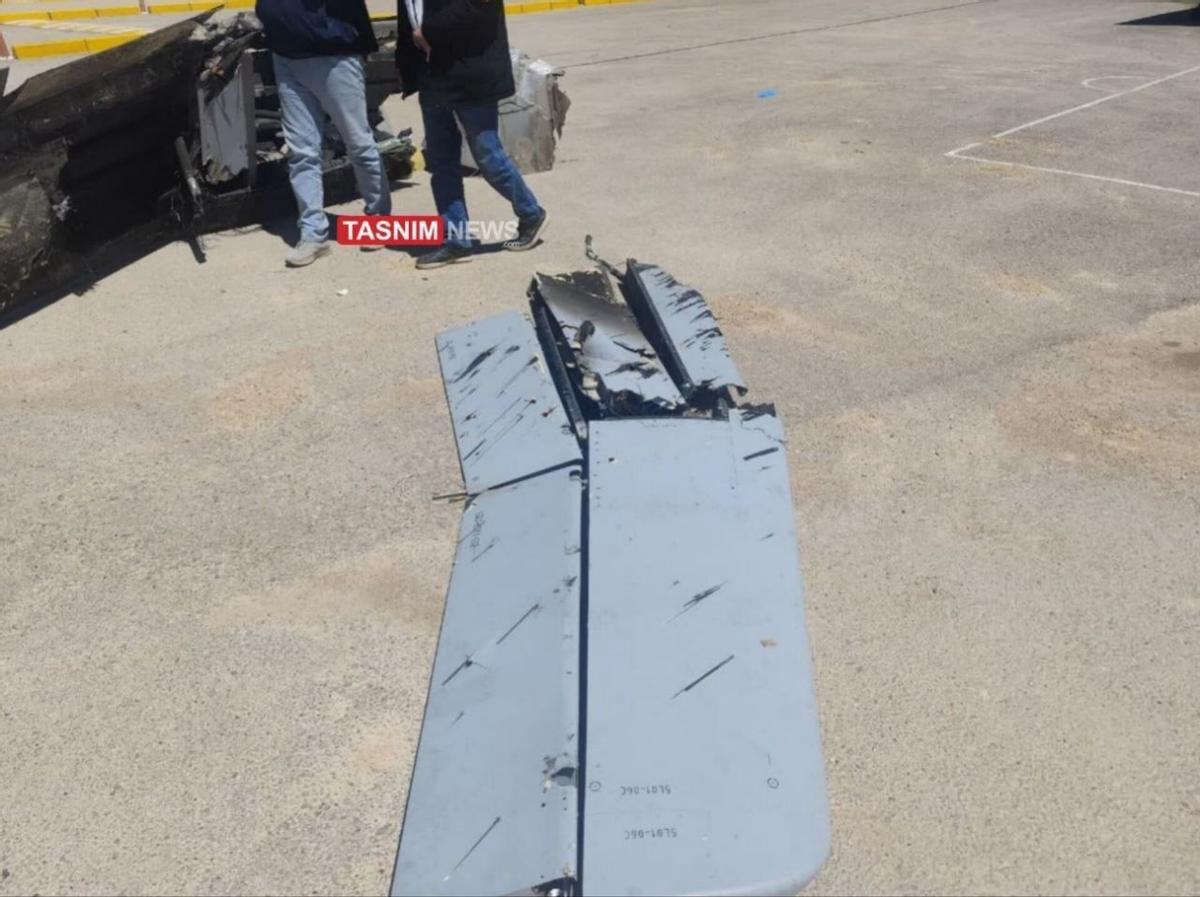 飞机残骸现场，调查正在进行中。飞机尾翼破损，现场有人在查看。