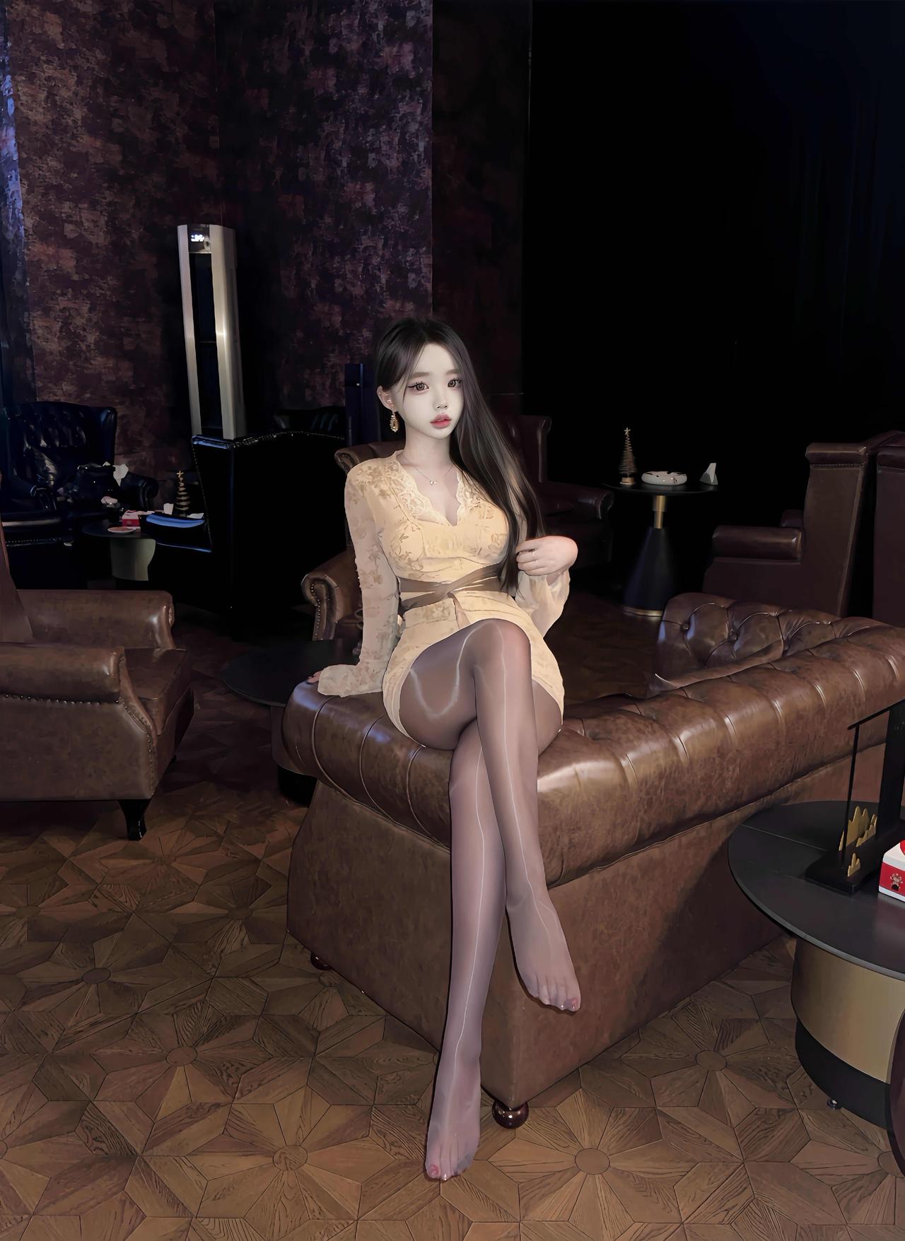 暖调灯光裹着棕皮沙发的纹路，蕾丝裙和柔光丝袜在暗里泛起细碎光泽。

指尖碰过裙摆