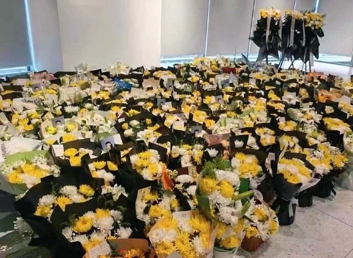 张雪峰公司楼下，花束挤挤挨挨地铺开了，像一片无声涌来的潮水。
每一束都带着卡片，