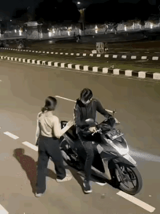 小伙子骑摩托车准备载女朋友出去兜风，当女孩要跨上摩托车时，男朋友故意逗她，往前开