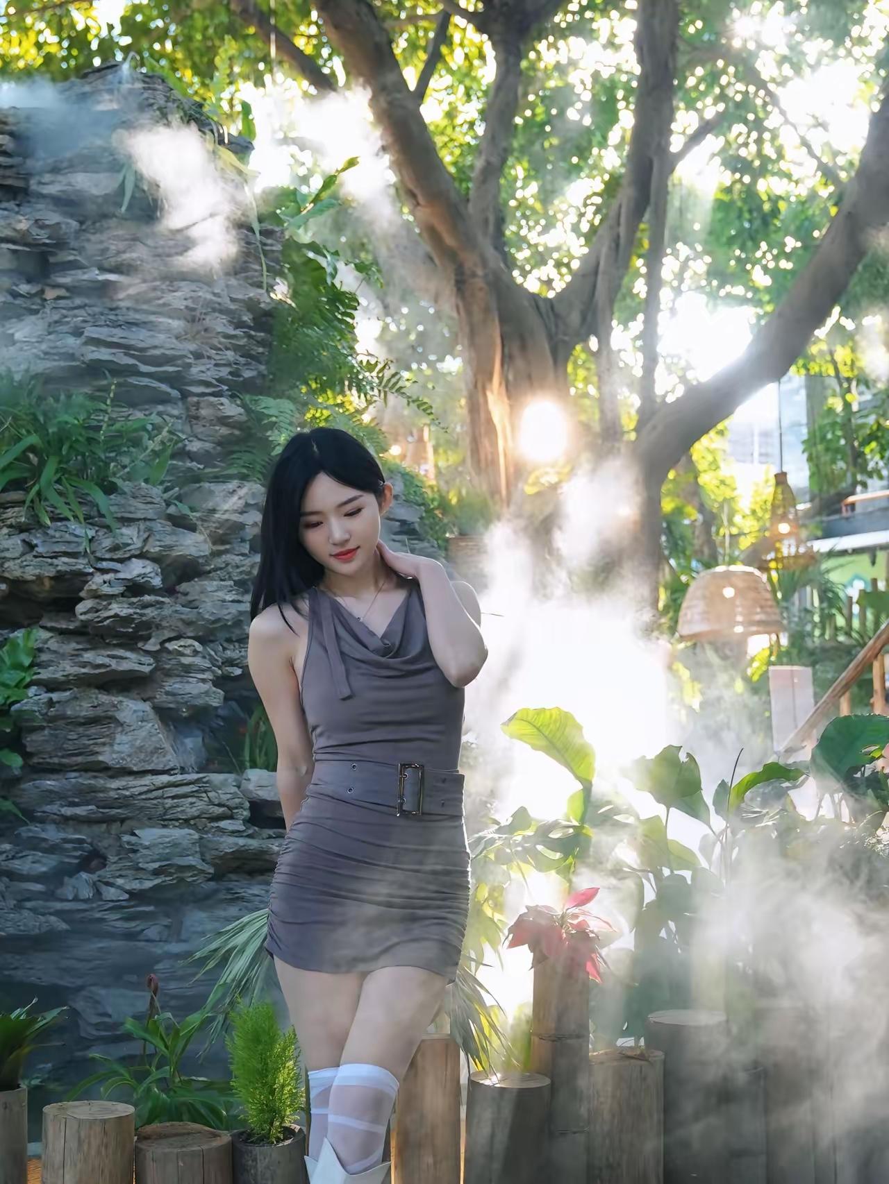 阳光洒落的花园，优雅女子在绿意中轻倚，仿佛置身仙境。