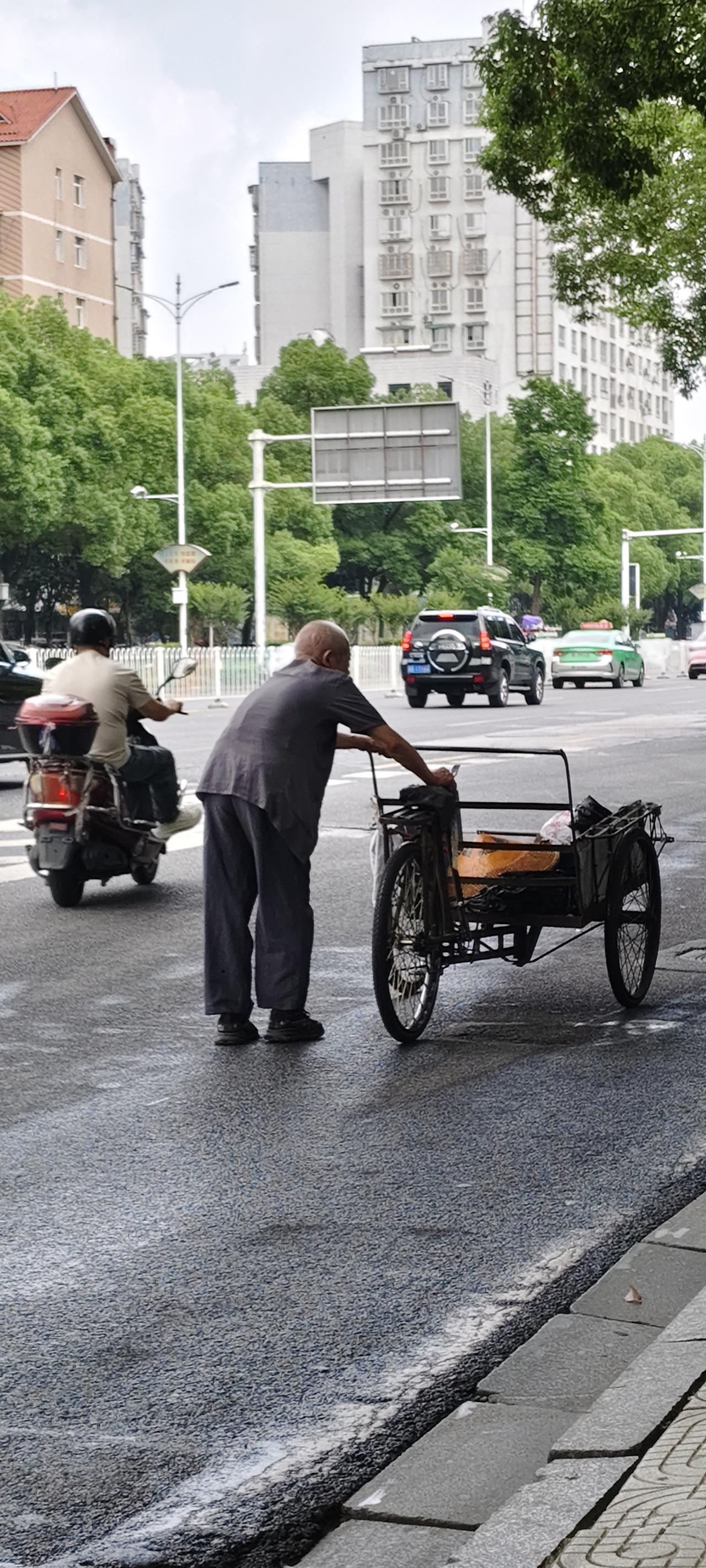 他推着废品车艰难行走
他佝偻着腰
推着小车缓缓而行
他头发已白
看上去是65岁以