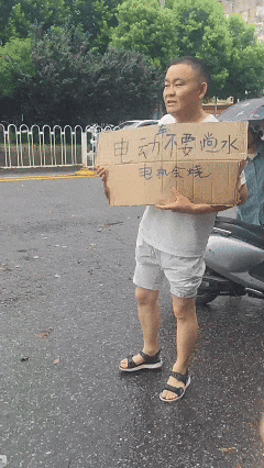 武汉暴雨中，44岁电动车老板路边举牌2小时，劝骑车人别蹚水，“不想靠修电机赚钱”