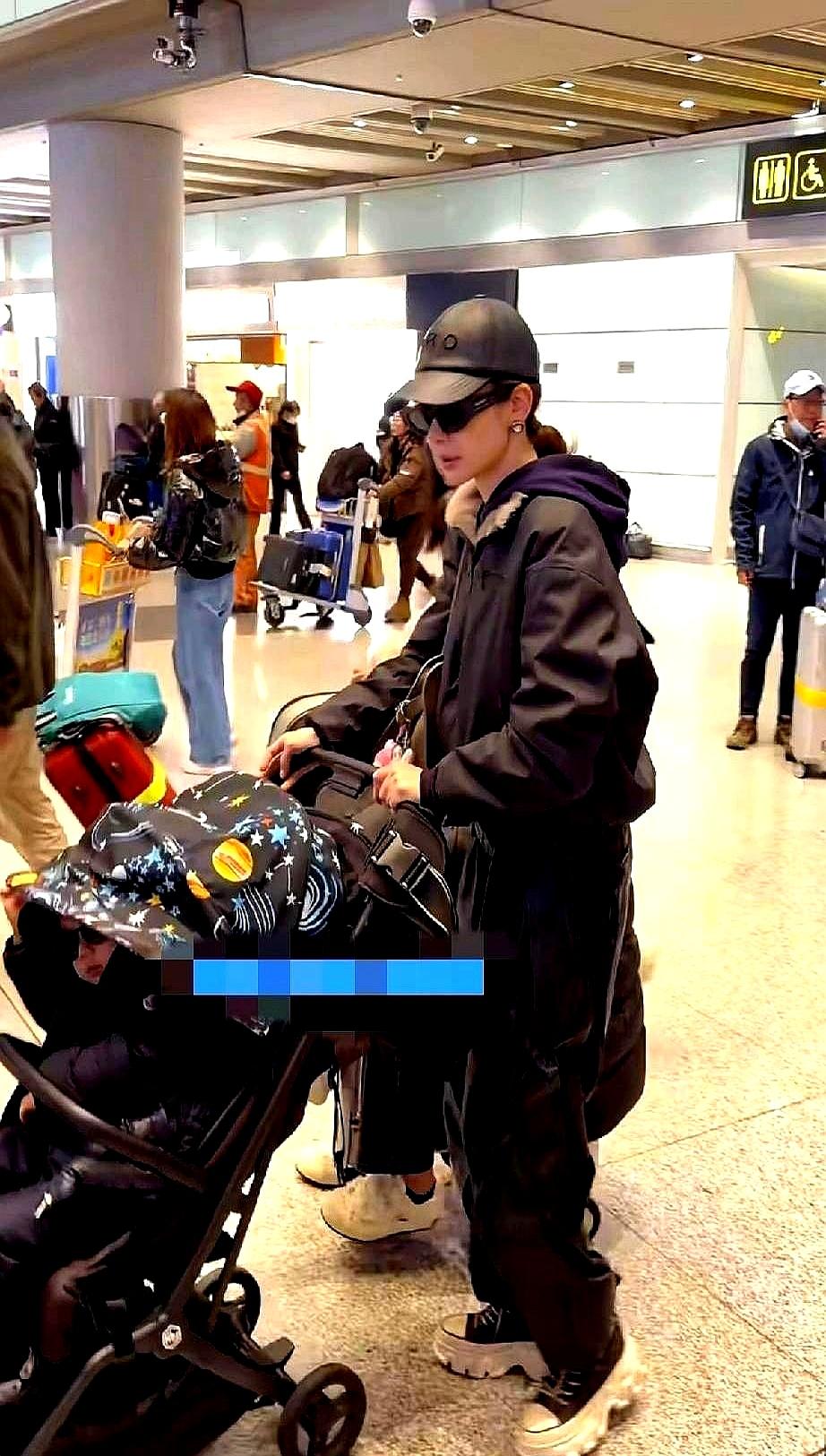 戚薇嘴唇发白，身体前倾着硬扛两个孩子。
 

机场里，她一个人推着婴儿车，儿子在