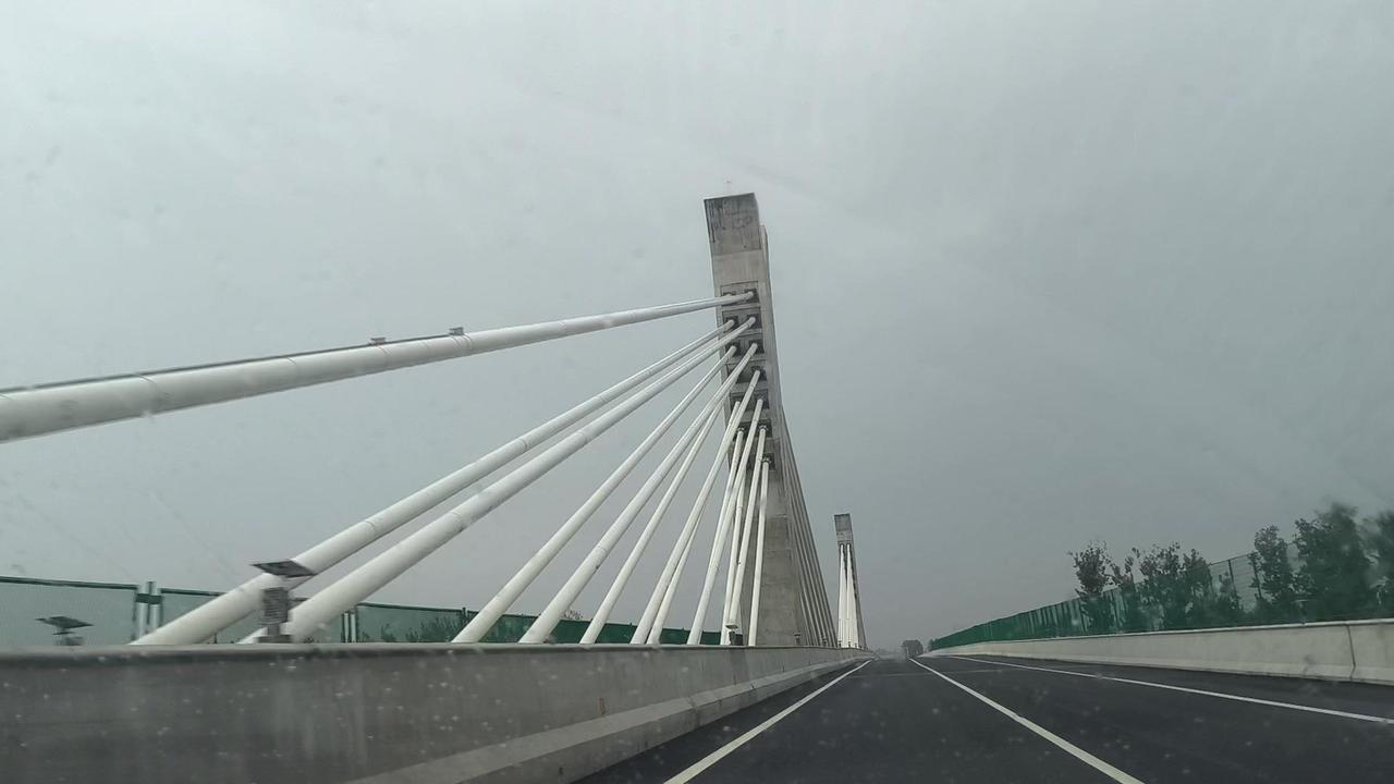 在高速桥上开车，突然发现阳光穿过桥身的钢结构，在路面投下斑驳的光影，像一幅动态的
