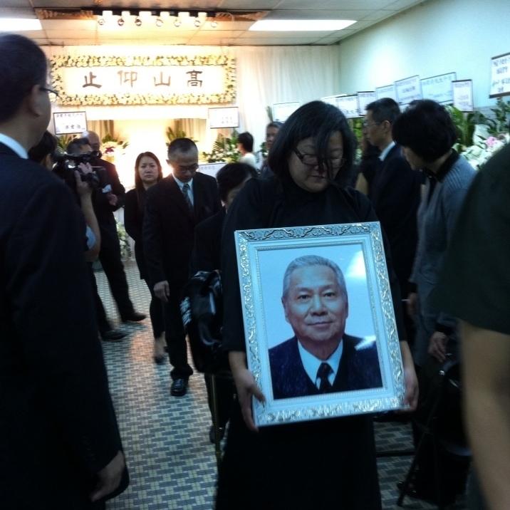 2012年，洪晃抱着父亲洪君彦的遗像出殡，一身素服，眼神中透露出伤心，这一刻的洪