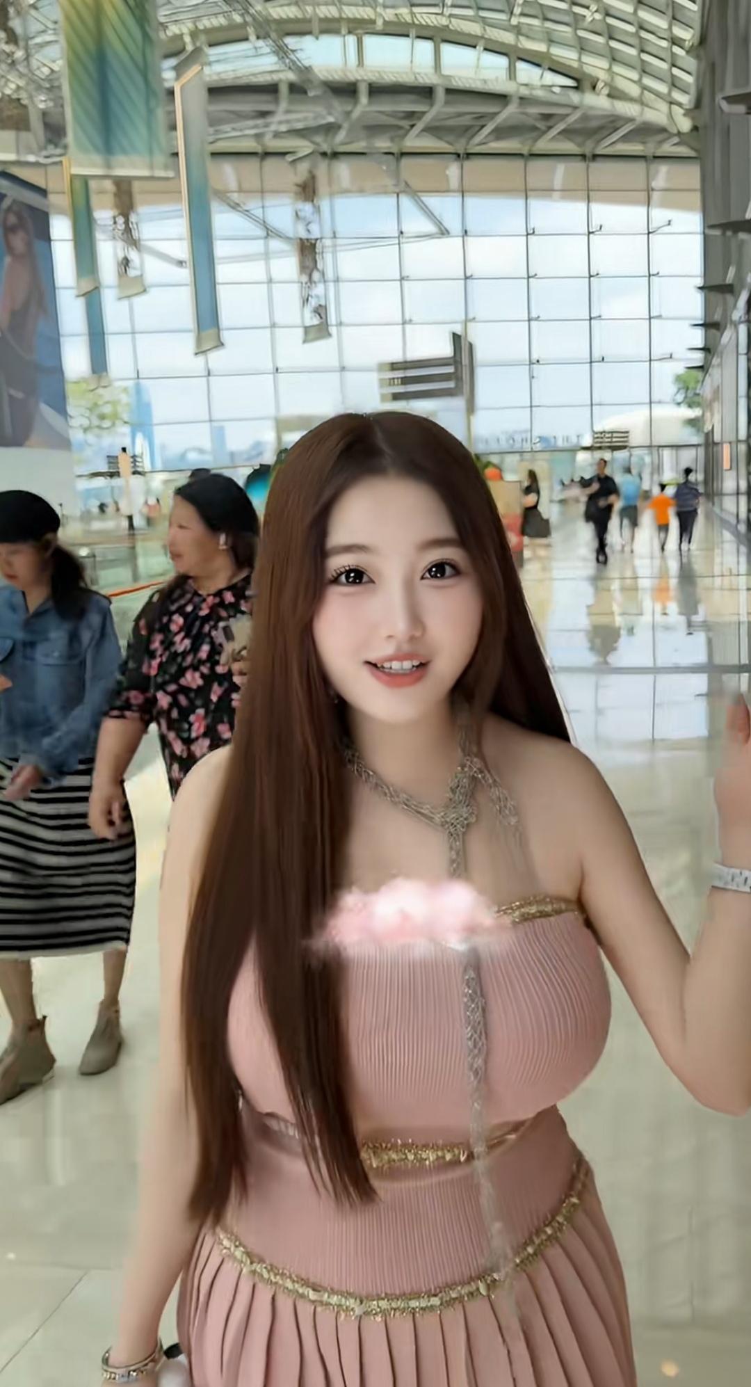 机场里，美女在自拍，背景人来人往。