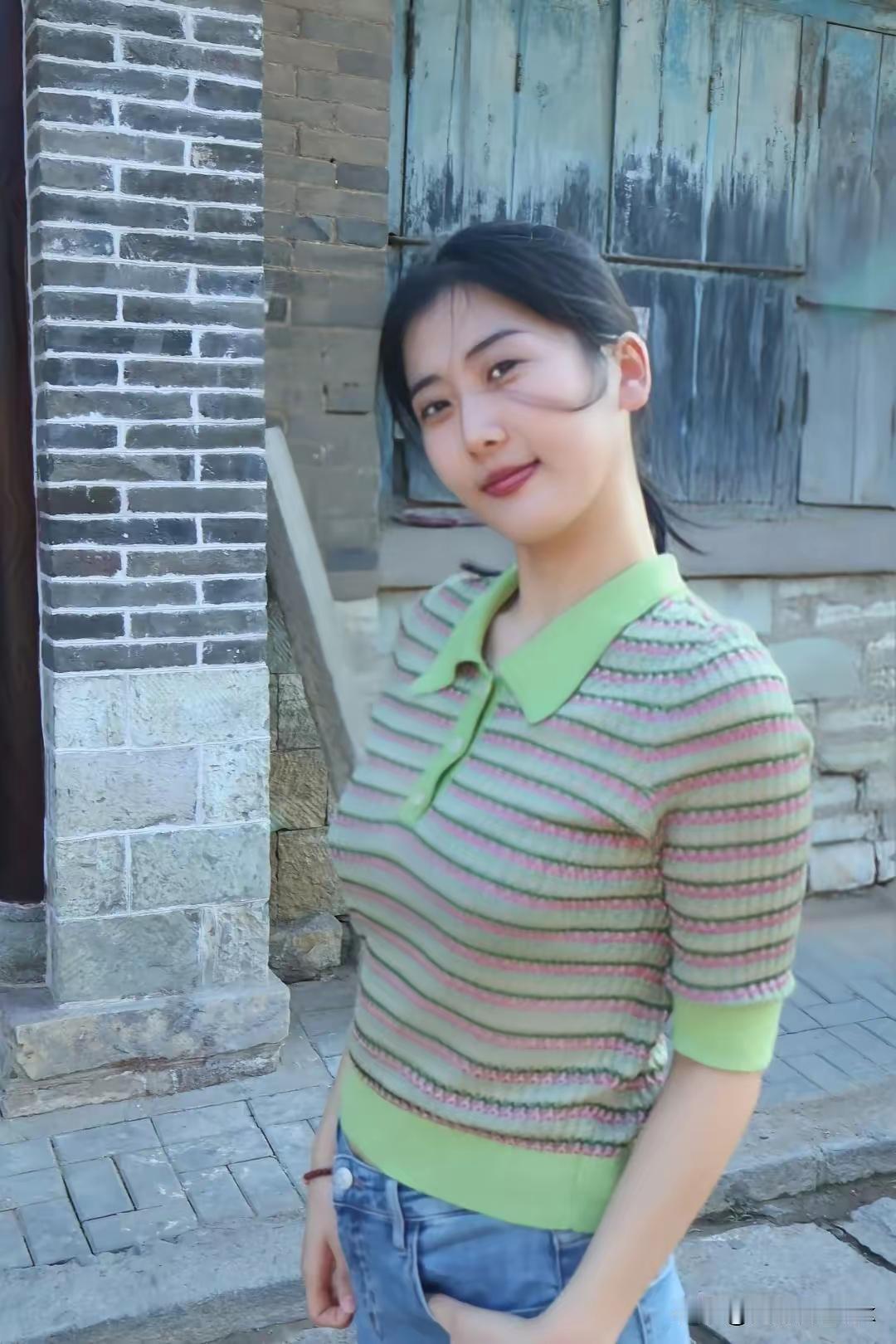 复古砖墙前，绿衣少女微笑，怀旧与青春的碰撞。