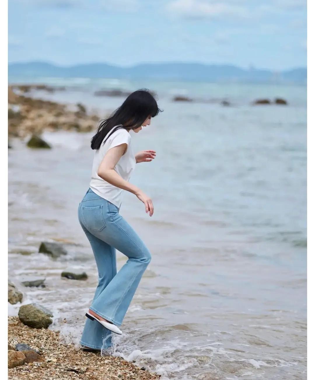 牛仔裤美女海边漫步，轻盈步伐，沙滩戏水，享受海风拂面的自由时光。🌊👗👠被牛