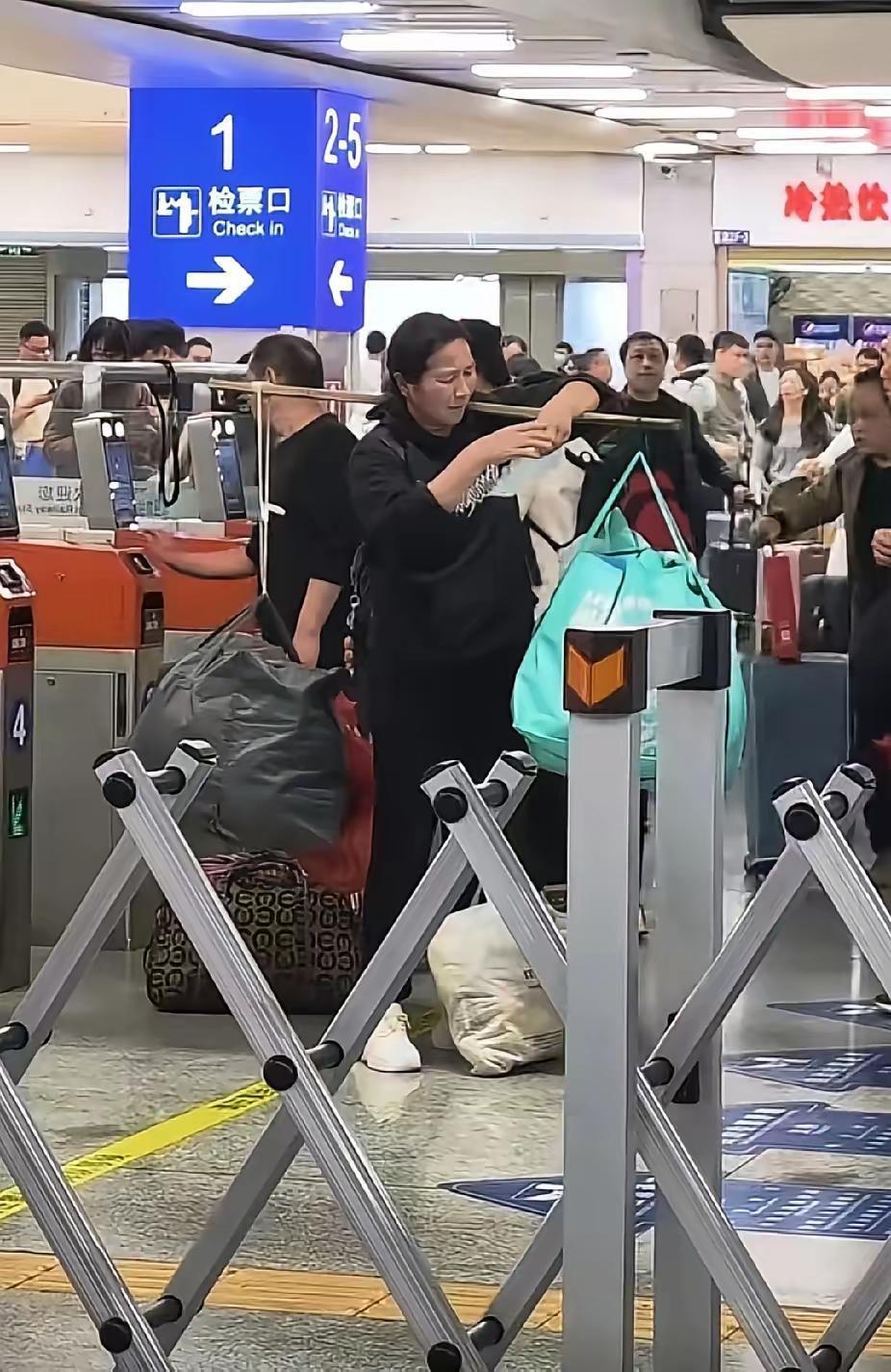 深圳火车站的检票口前，有位大姐正用扁担挑着两大袋鼓鼓囊囊的行李，脚边还放着个拎得