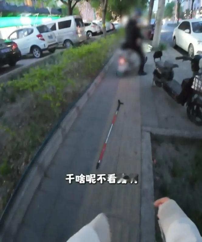 一个盲人姑娘在盲道上被逆行电动车撞倒，还被骑车人骂不看路。她在地上摸索盲杖，委屈