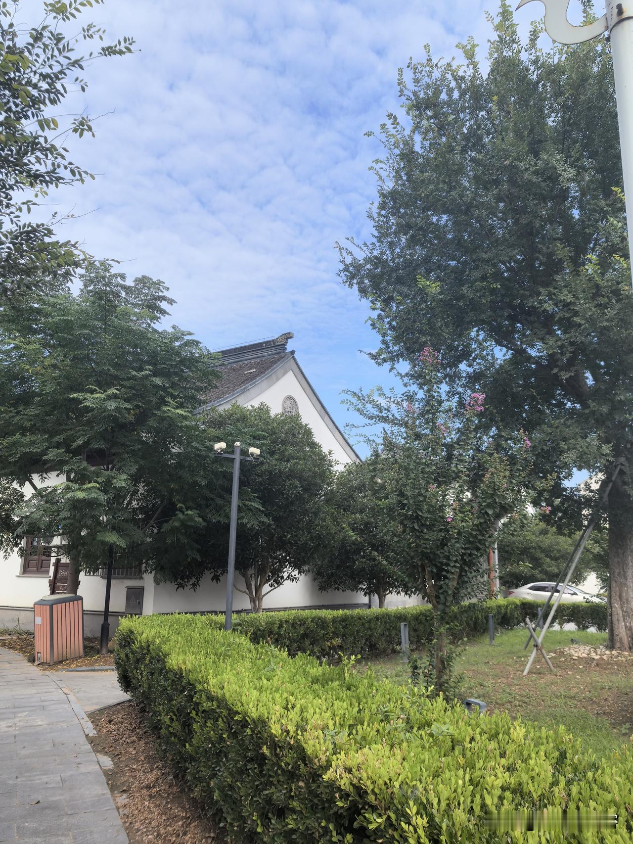 修剪整齐的绿篱沿着小路铺开。抬眼望去，蓝天铺得开阔，云丝轻轻散开，清清爽爽；古式