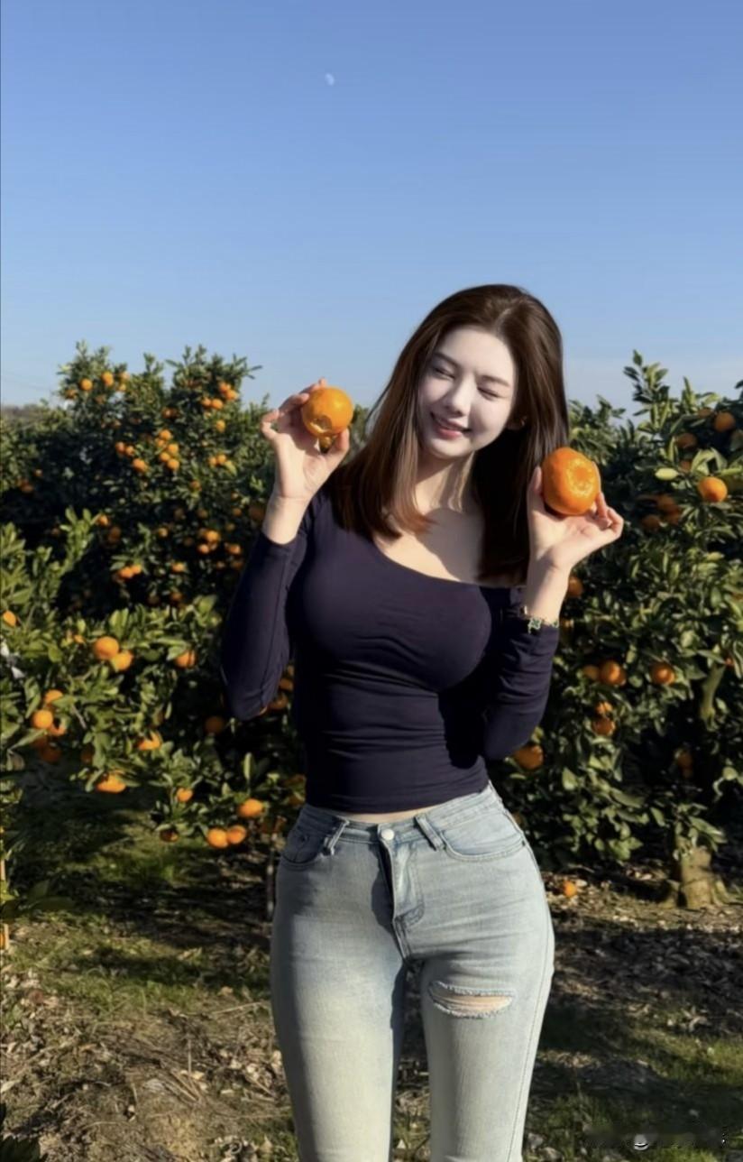 这是一个绝美的画面，美女置身山上果园，周围满是橙树，金黄的橙子挂满枝头。她伸手摘