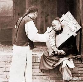 1905年，一名犯人仍戴着枷锁，他的家属正在给他喂饭。 ​​​