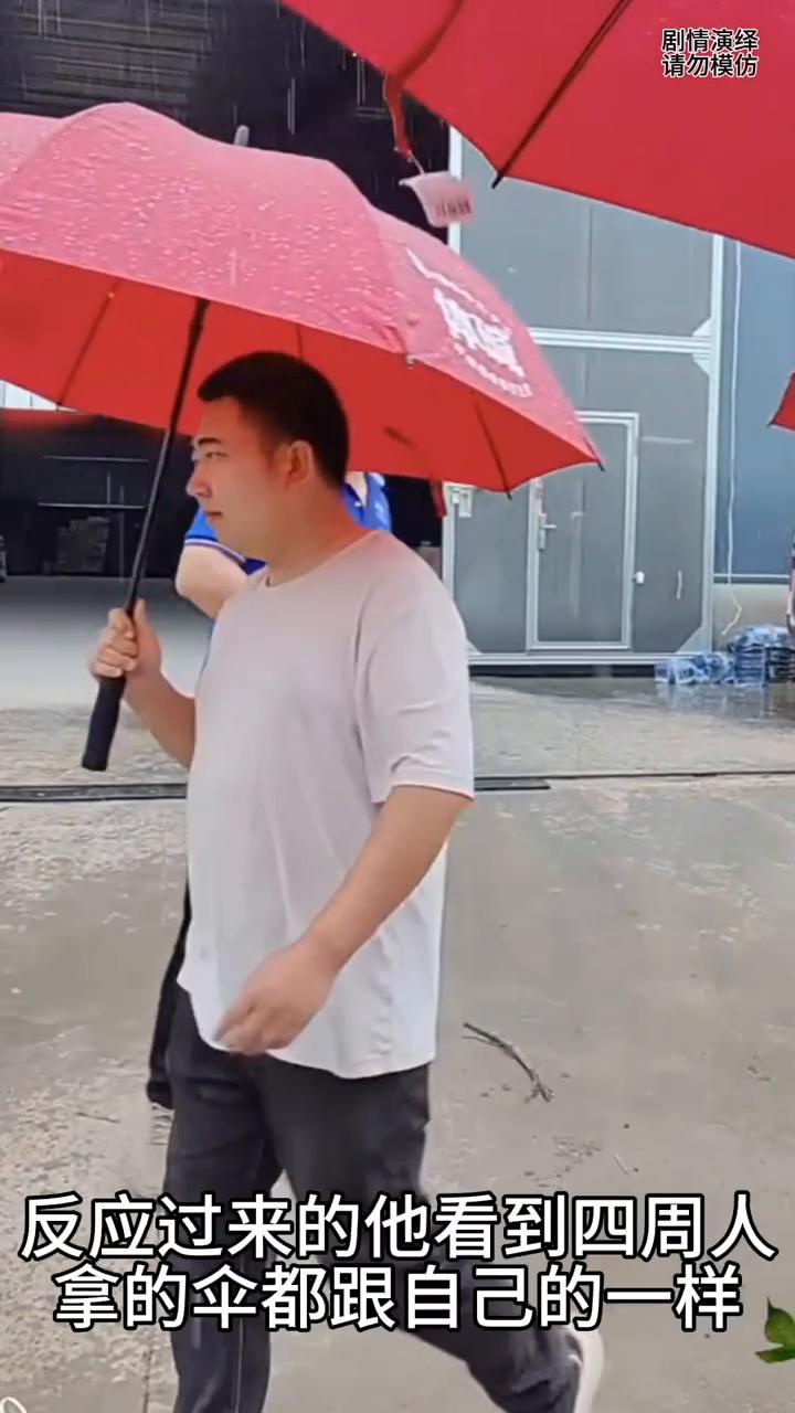男子看手机时雨伞被别人拿走了，下一秒他的举动太无奈了。
男子拿着伞时看着手机，这