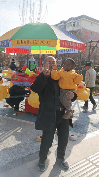 老人抱着一个小孩子正在拍视频。
两个人看起来笑的都非常开心？
也不知道这是孩子的