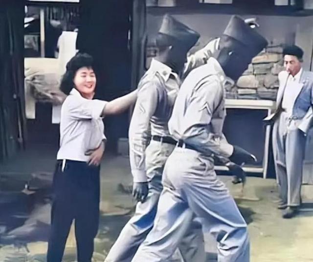 1952年，一名南朝鮮女子给两名美军做完服务后，当着老公的面热情地送大兵们离开。