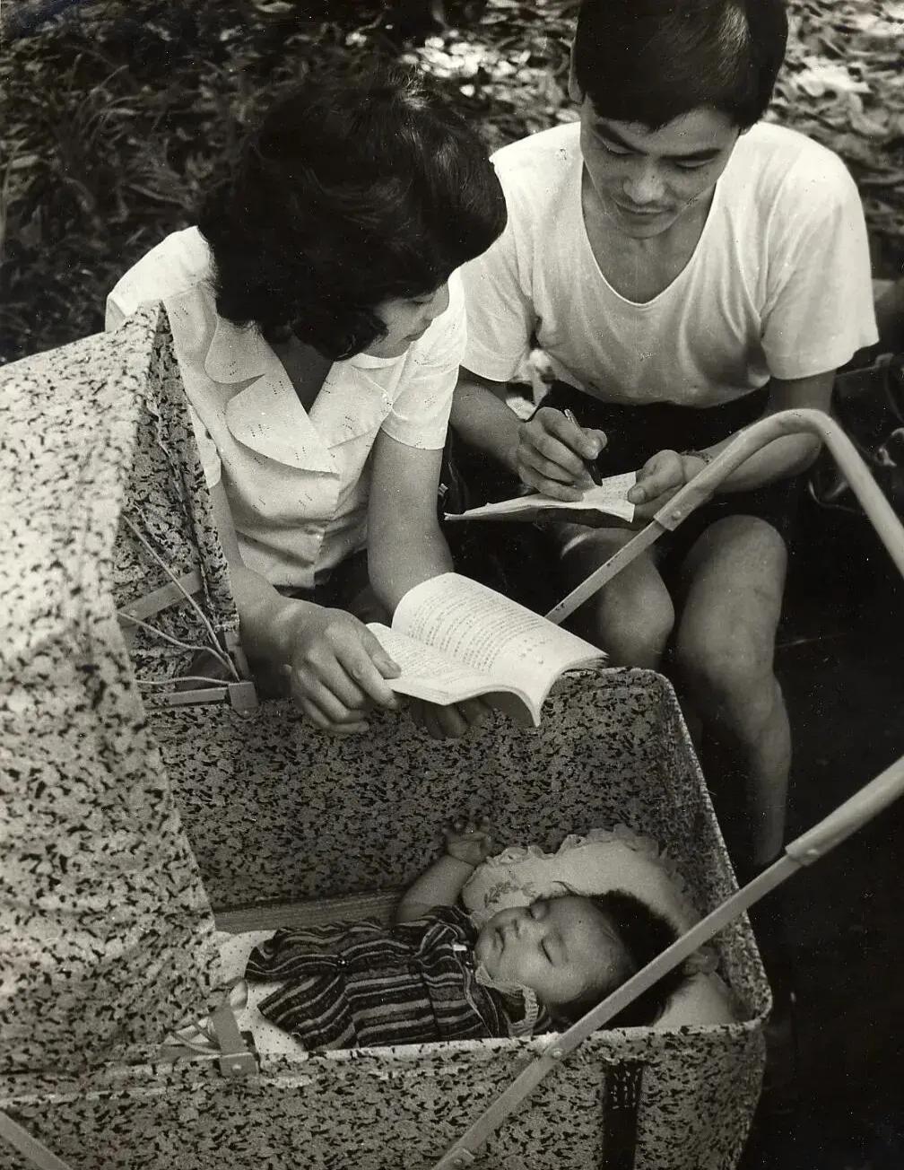 1983年夏天，上海复兴公园里的一家三口，孩子在精致的儿童车里熟睡，年轻的夫妻看