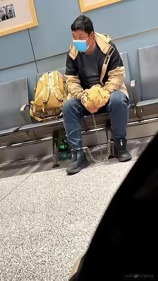 这个男人戴着手铐，戴着脚镣，神情自若的坐在火车站的座椅上，眼睛张望着远方，在他的