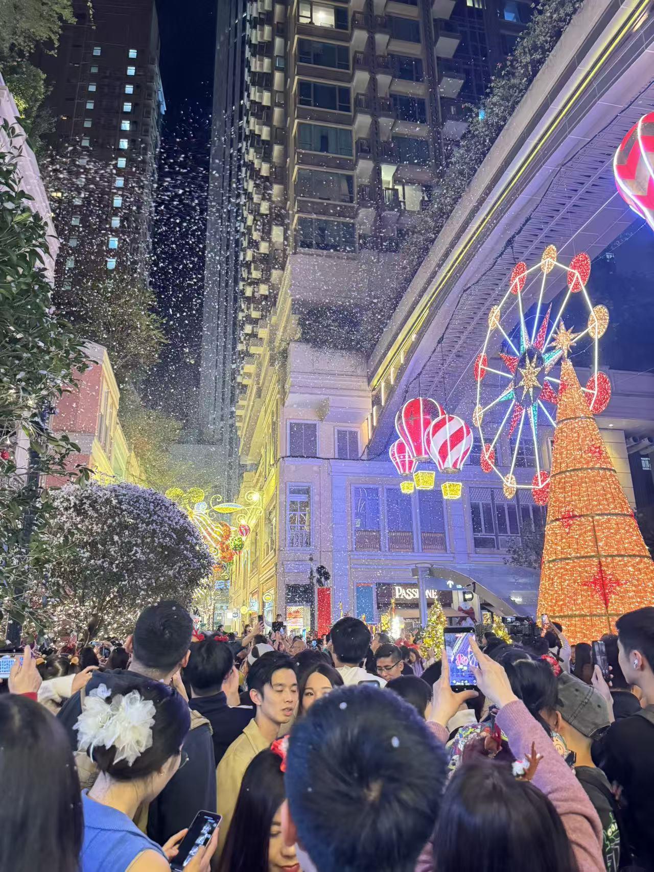 夜晚街头，人群聚集，圣诞树亮起。