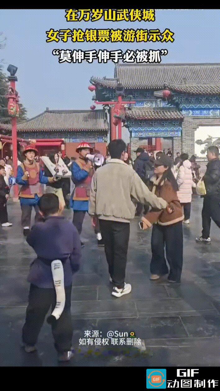 女子身扛枷锁，被两名官兵押着游街，其中一人手里举着扩音喇叭，边走边用喇叭高呼：“