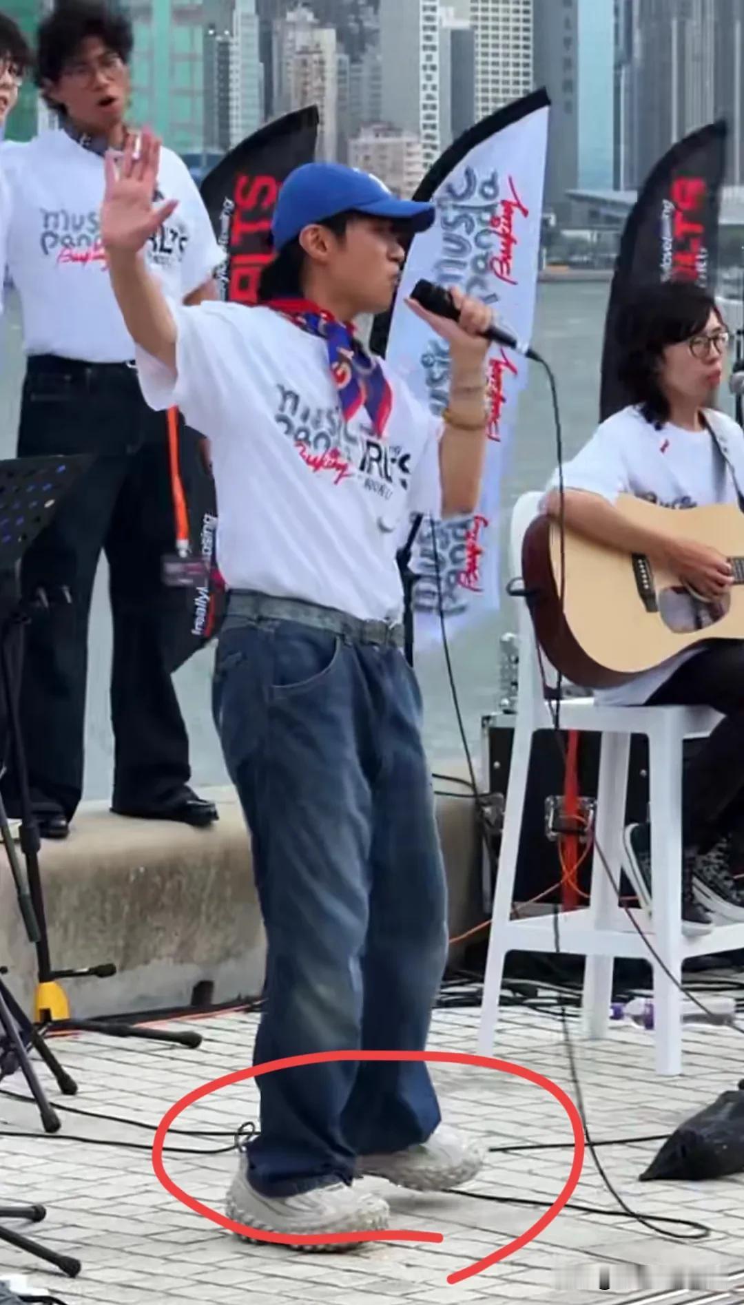 古巨基香港街头献唱，歌曲劲爆十足，蓝色棒球帽，白色恤衫搭配怀旧风格的牛仔裤，脚上