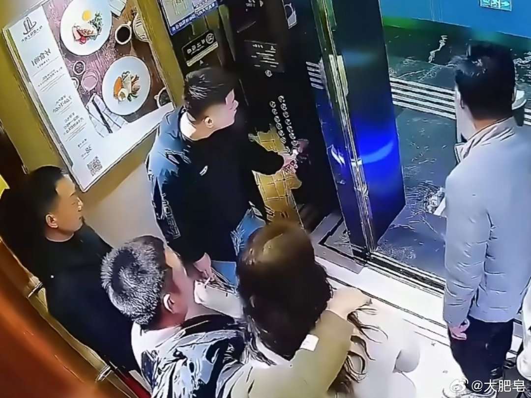 机器人正要进电梯被男子一脚踹倒 右手搂个妹子，小脚直接一踹，把机器人踹倒，显得自