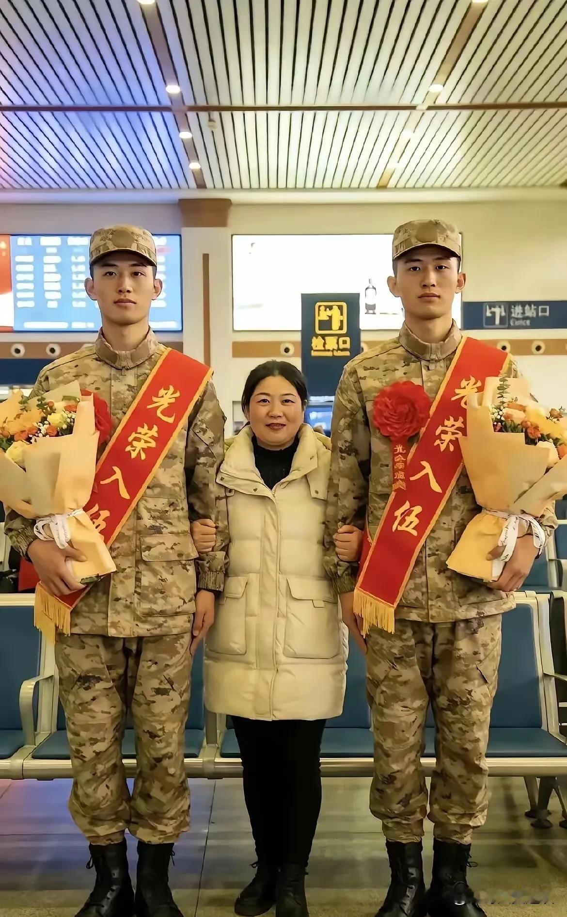 这是世上最自豪而最幸福的妈妈。一对双胞胎儿子入伍，妈妈站在中间，拉着两个儿子的手