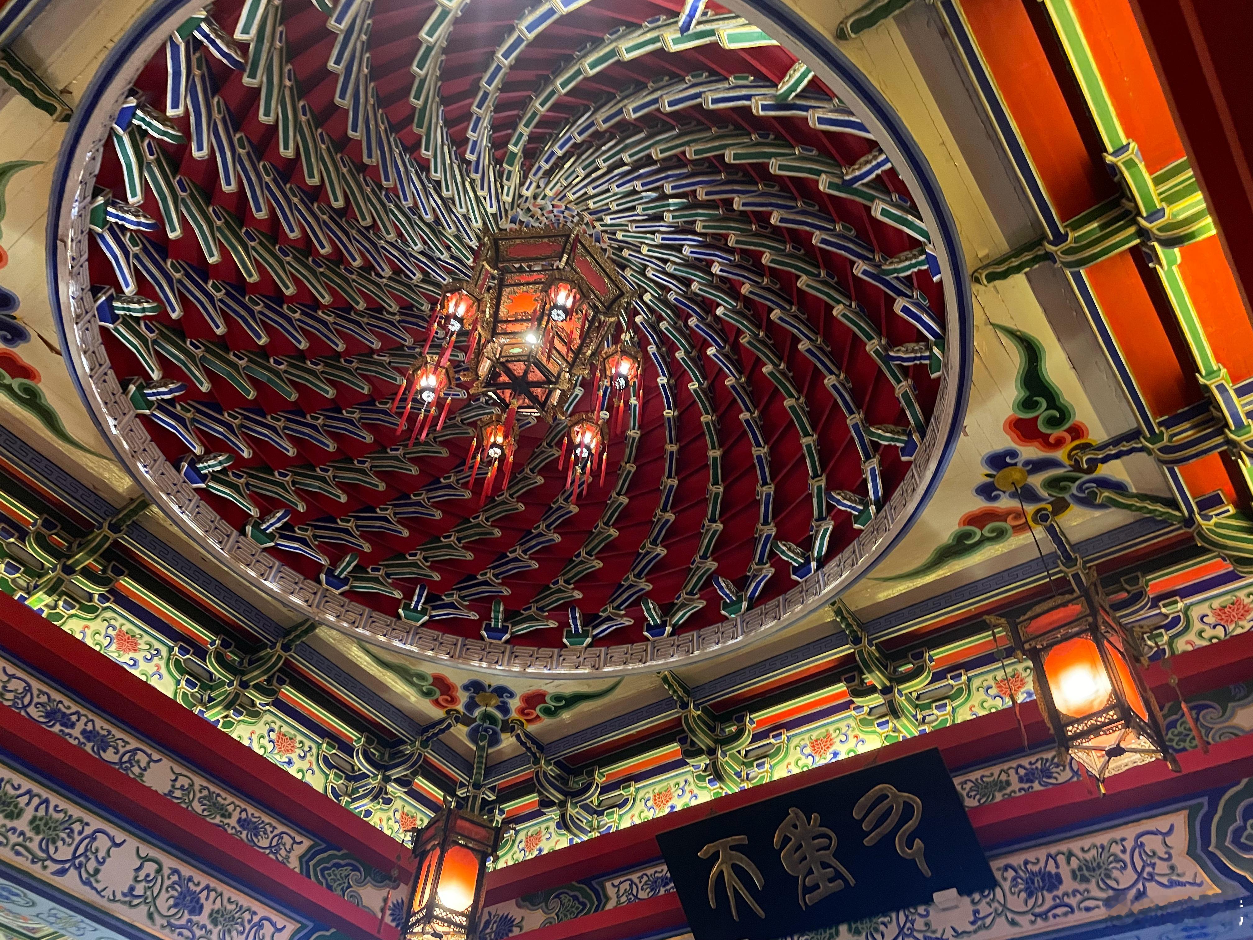 南昌滕王阁古建藻井，螺旋结构如旋涡般灵动，红、金为主的色彩浓烈华丽，雕花与灯盏对