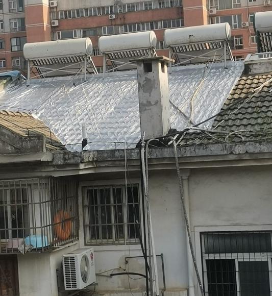 我们小区一户人家把屋顶铺上了这个白色的膜，不知道是不是为了防晒。
我们家也住顶楼