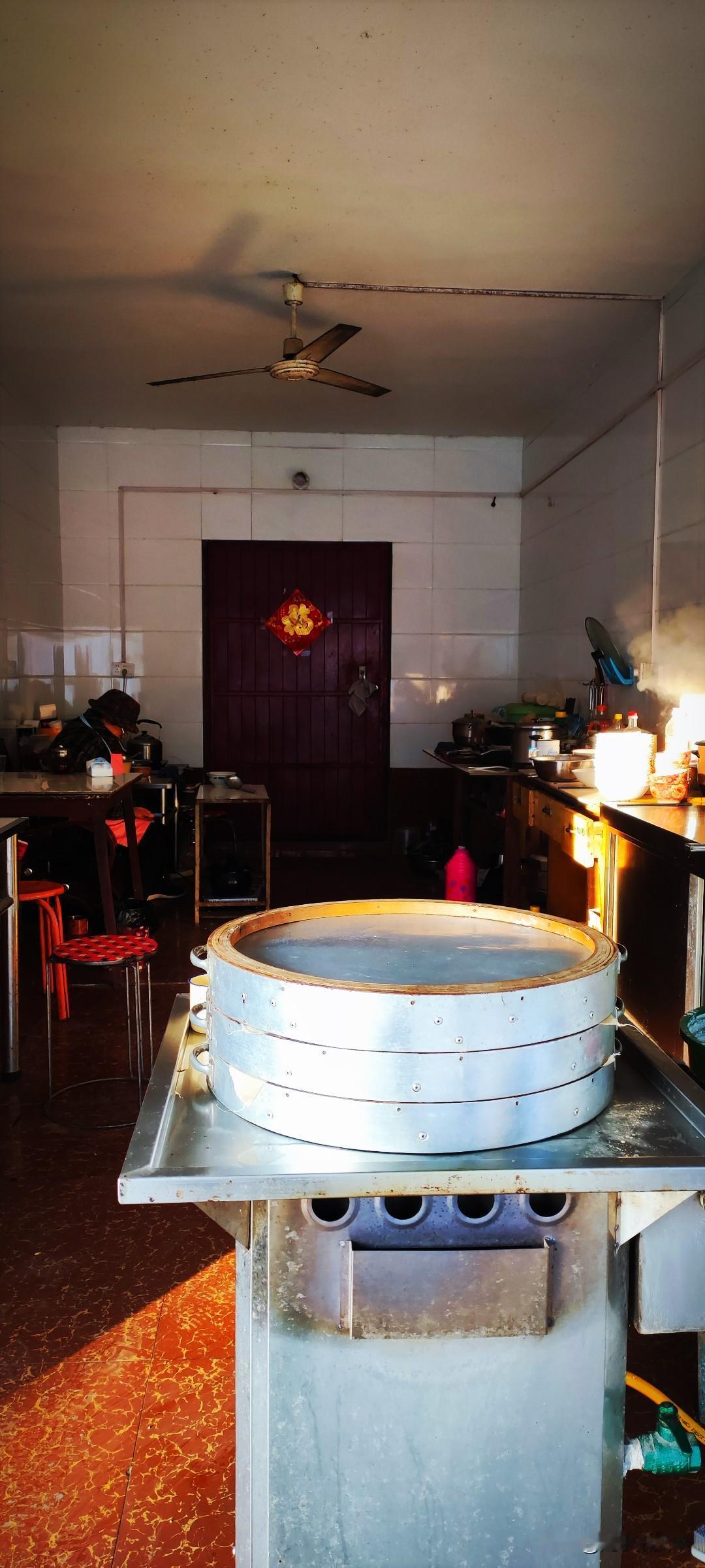 随手拍张照清晨的阳光斜斜地溜进面皮店，大妈等着食客：笼屉静置在炉子上，案子上一溜