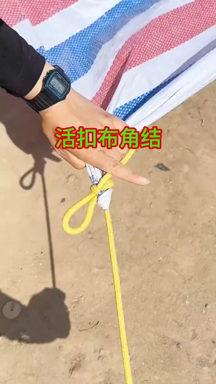 活扣布角结。
·第一步：把布角捋一下，绳子放在下面。
·第二步：绕个圈，套住绳子