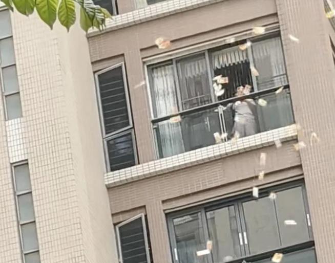 4月14日汕头星湖城，一位大妈从高层阳台往下撒500、1000面值的港币，钞票漫