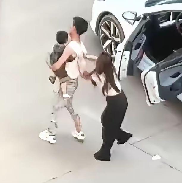 丈夫怀里抱着孩子，妻子追上来连踹带打。他踉跄了好几下，差点连人带娃摔在地上，却始