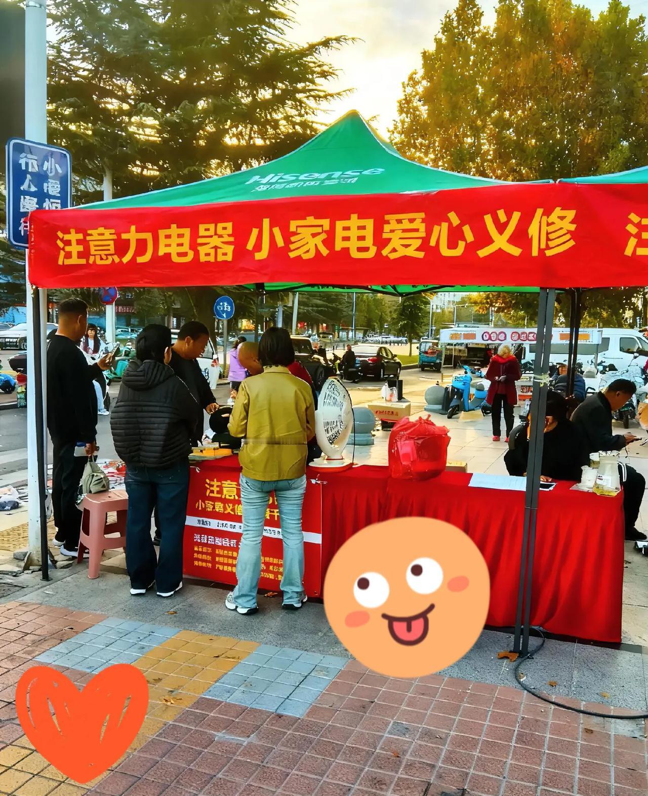 在街头的一角，注意力电器的“小家电爱心义修”摊位格外醒目。师傅们在红色桌布的工作