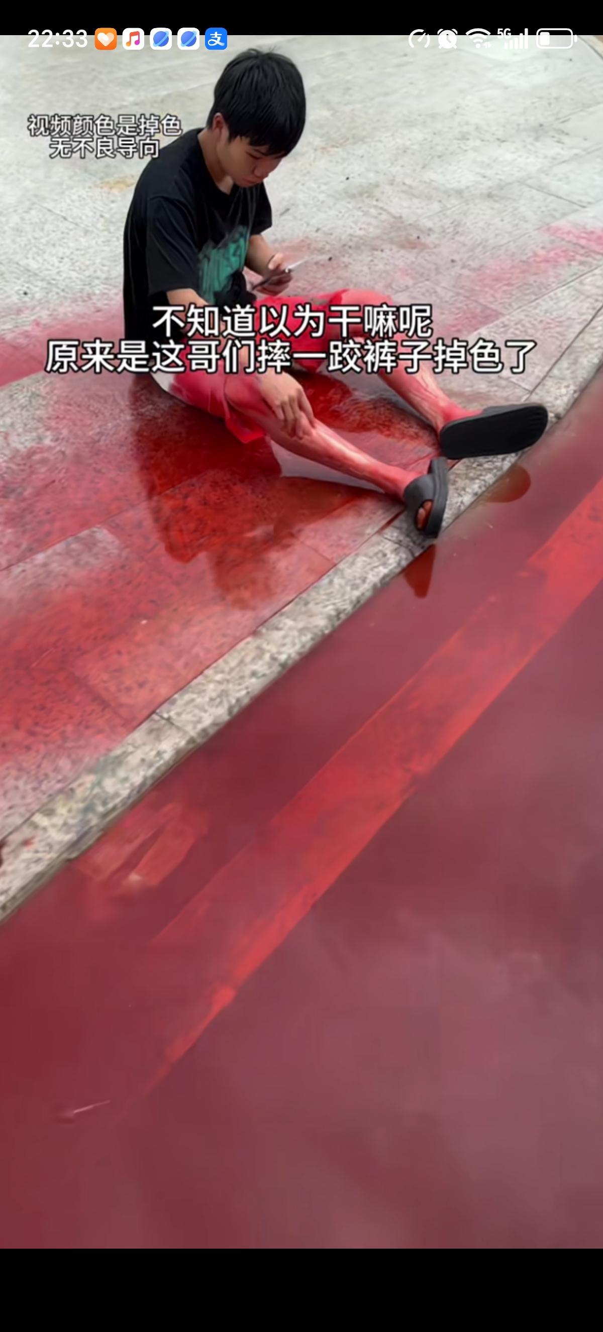 男子走路时不小心摔倒在路边的水坑里了，他身上的红色大裤衩子严重掉色，红色染料顺着