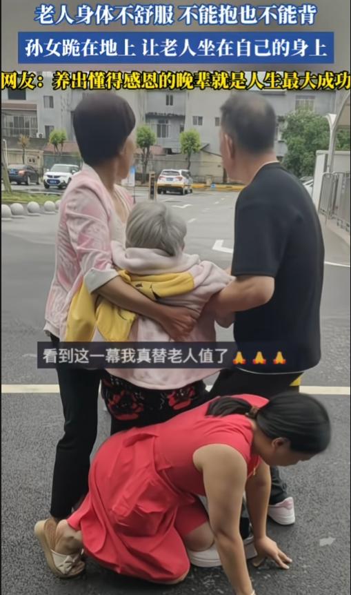 一老人就医途中，体力不支，既不能抱也不能背，孙女跪在地上，让老人坐在自己的身上。
