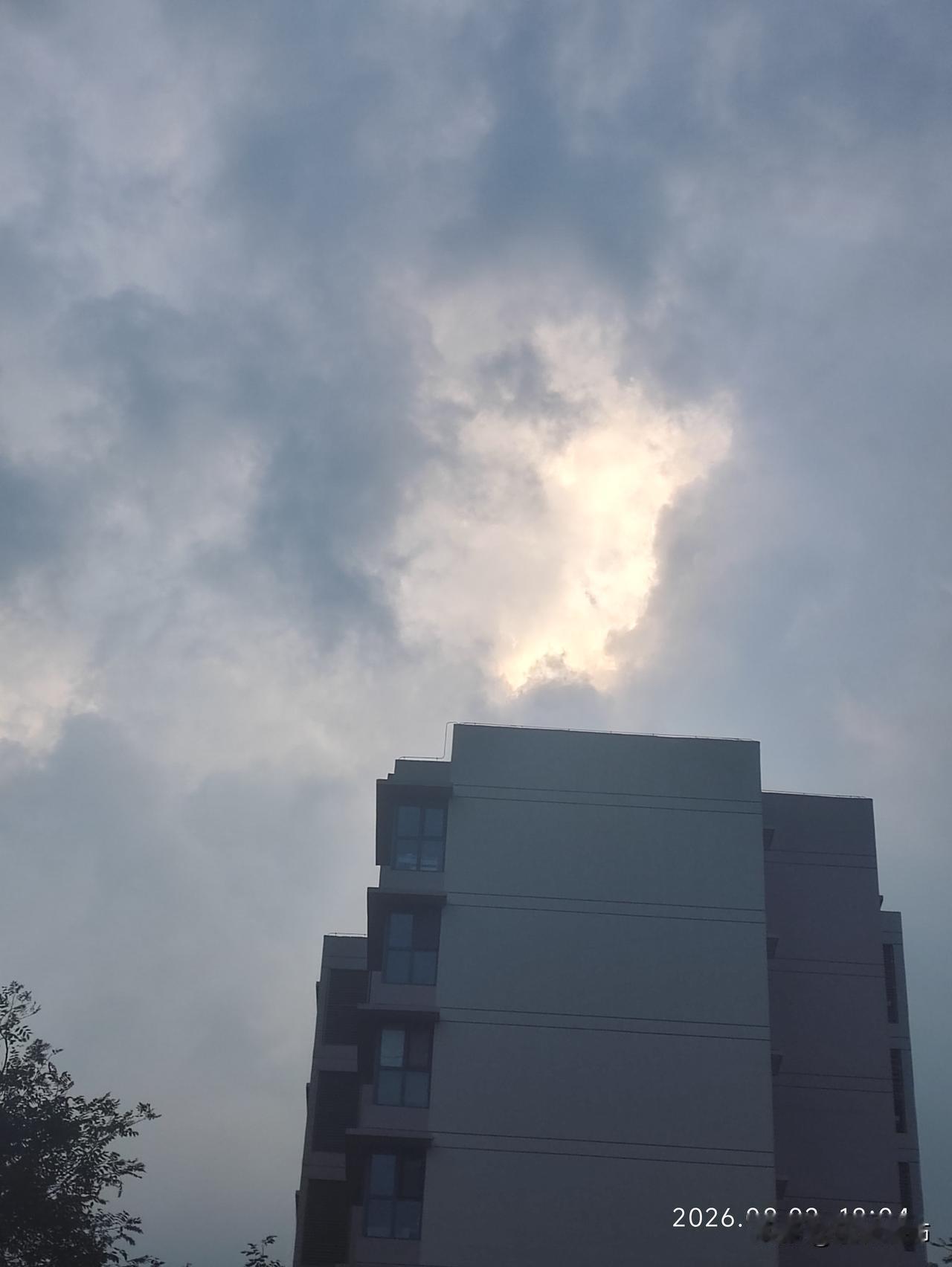 暮色漫过楼宇，云朵被落日悄悄晕染。原本灰白的云层，破开一道温柔金光，霞光漫涌开来