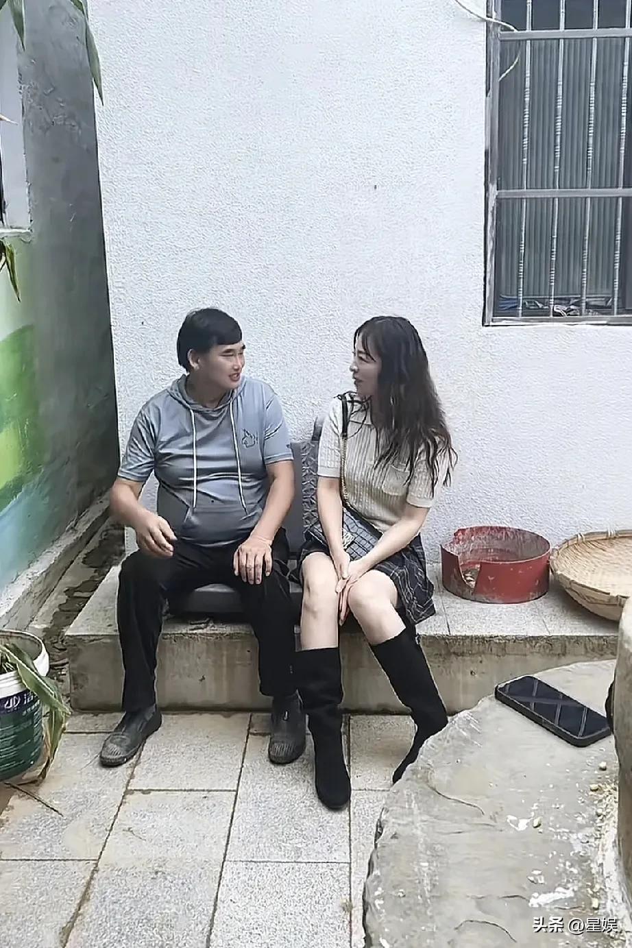 大衣哥和粉丝两人坐在墙边聊天，气氛轻松。