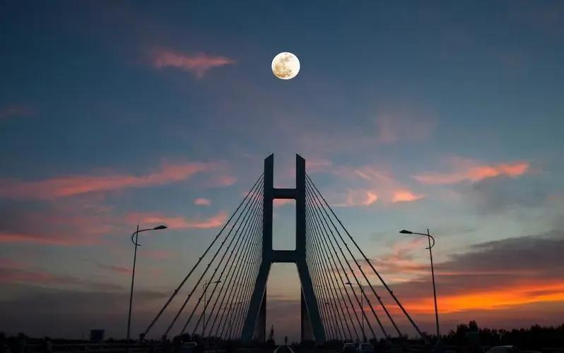 桥上行驶晚霞红，
云卷云舒映水东。
车窗轻掀风送暖，
心随景动梦中踪。

远山如
